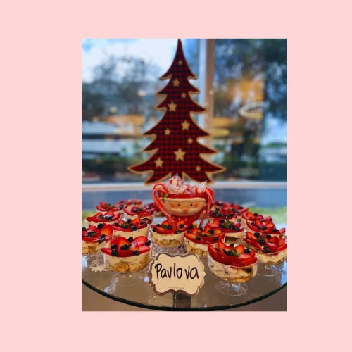 Mini pavlova cups displayed with strawberries and blueberries, arranged for a holiday celebration event dessert table