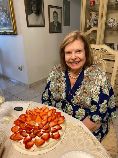 Happy customer smiling at home with a fresh strawberry pavlova cake, sharing a top pavlova bakery near me review for CakeMiami in Miami
