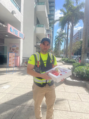 First Responder holding fresh pavlova near me on Design District sidewalk, picked up from CakeMiami’s pavlova bakery in Miami