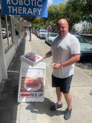 Smiling customer picking up a fresh pavlova near me at Pavlova Bakery Coral Way, a local favorite in Coral Gables