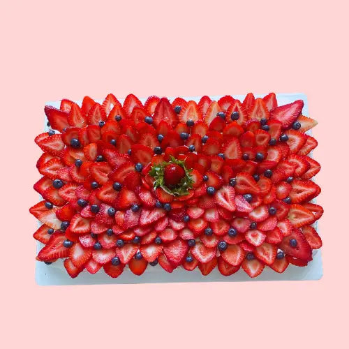 Large pavlova cake decorated with strawberries and blueberries in a layered flower pattern, 19-inch rectangular shape for events or celebrations