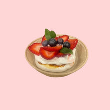 Mini pavlova cake with piped whipped cream and fresh strawberries on top, ideal for elegant dessert presentations