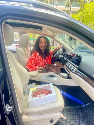 Happy customer in her car with fresh pavlova near me from CakeMiami’s Wynwood location, ready for pickup