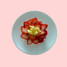 Individual mini pavlova cake with pineapple and strawberry arranged as a flower, topped with whipped cream on meringue base