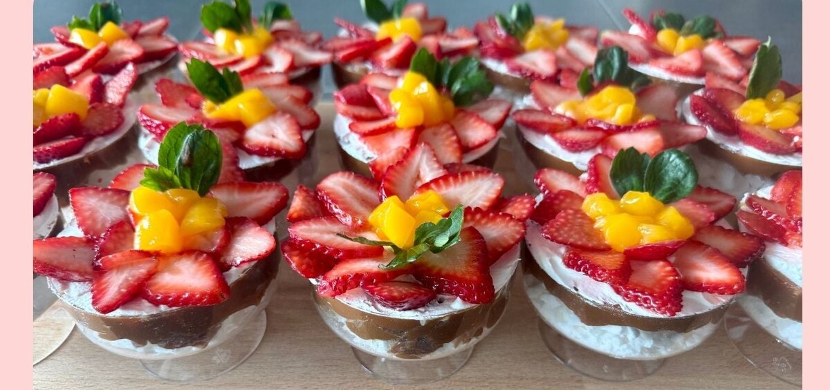 Mini pavlova cups topped with strawberries and mango on a tray